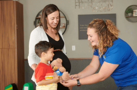 Daycare teacher giving child a New Horizon Academy teddy bear