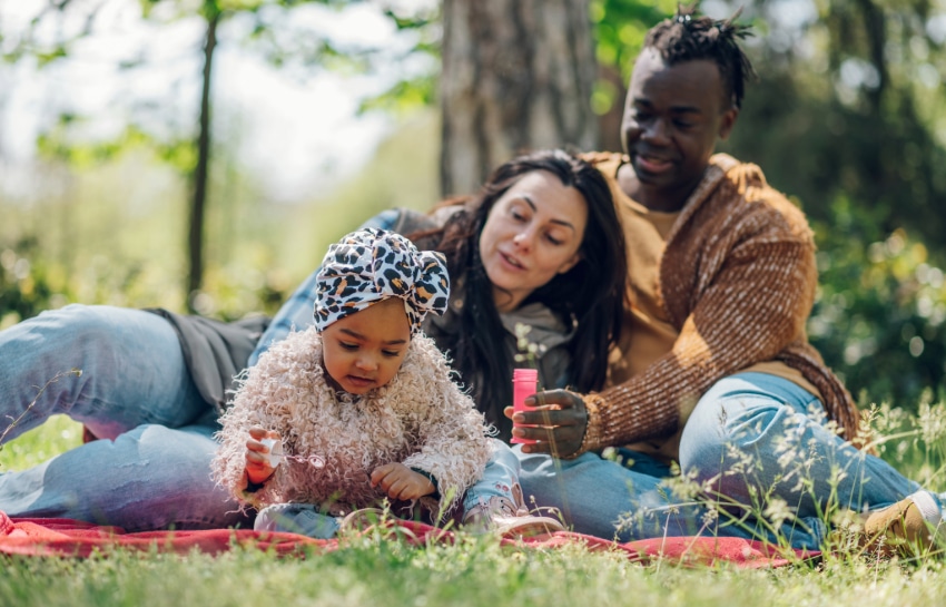 toddler and parents playing with bubbles outside