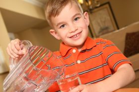 school-age child pouring a glass of water to stay hydrated