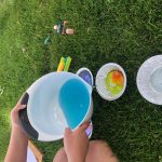 Pouring bubbles and food coloring into shallow bowls
