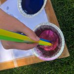 Dipping a straw into bubble and food coloring mixture