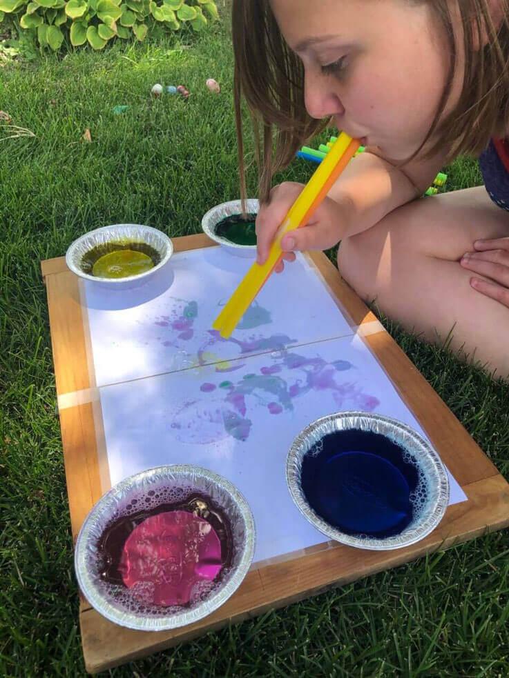 School-ager making a bubble art painting outside