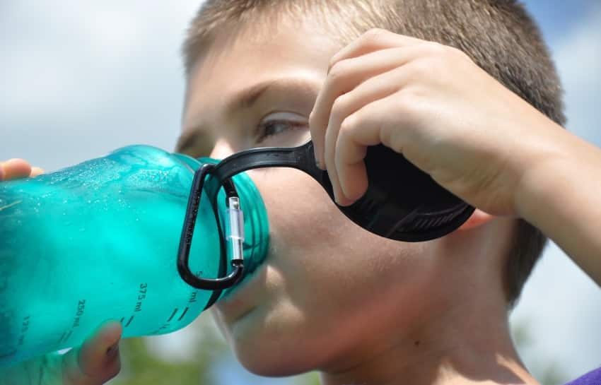school-age boy drinking water to stay hydrated