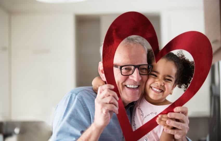 Grandparent and grandchild hugging and holding a heart for Valentine's Day