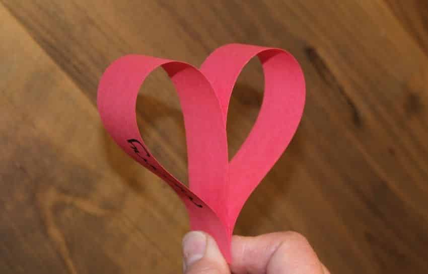 Red construction paper shaped into a heart to make a heart garland
