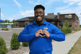 Childcare teacher with heart hands outside New Horizon Academy school