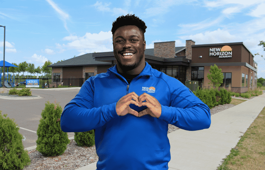 Childcare teacher with heart hands outside New Horizon Academy school