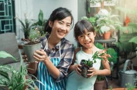 Mother and Daughter Smiling and Holding Plants