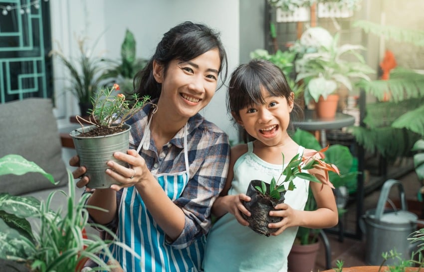 Mother and Daughter Smiling and Holding Plants