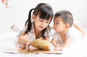 Brother and Sister Reading A Book Together