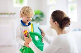 mother handing child backpack before school