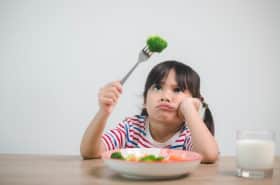 little girl not eating vegetables on her plate