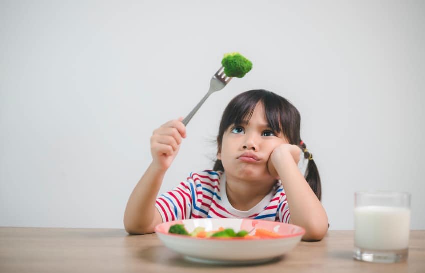 little girl not eating vegetables on her plate
