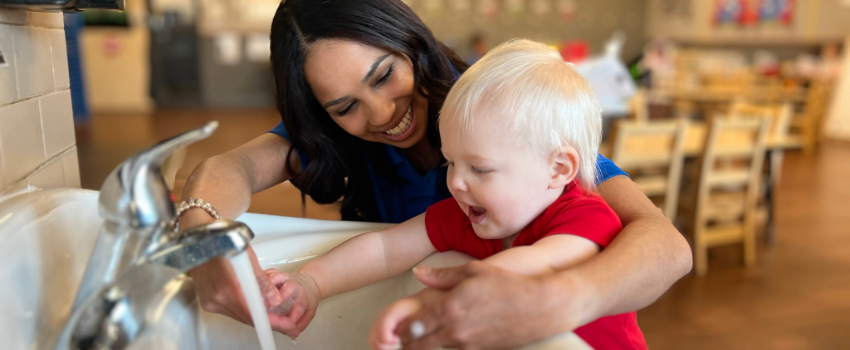 Daycare teacher practicing handwashing with toddler in the classroom
