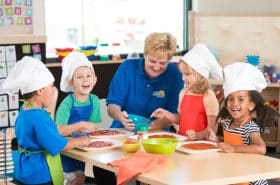 group of kids making pizzas with teacher