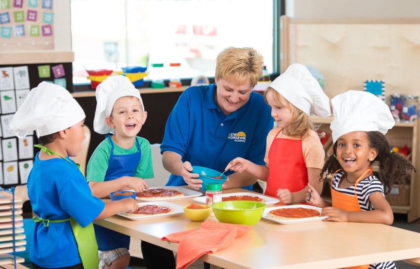 group of kids making pizzas with teacher