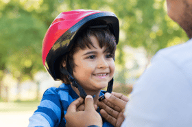 Parent helping child put on a bike helmet for safety