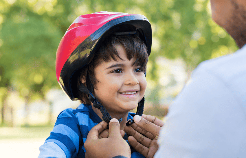 Parent helping child put on a bike helmet for safety