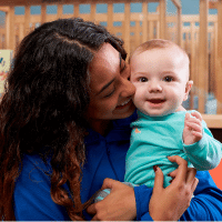 infant teacher hugging infant at daycare