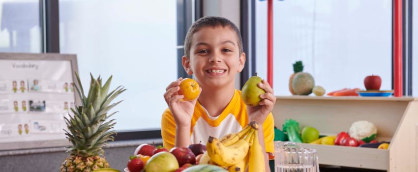 Preschool child holding healthy fruits at daycare