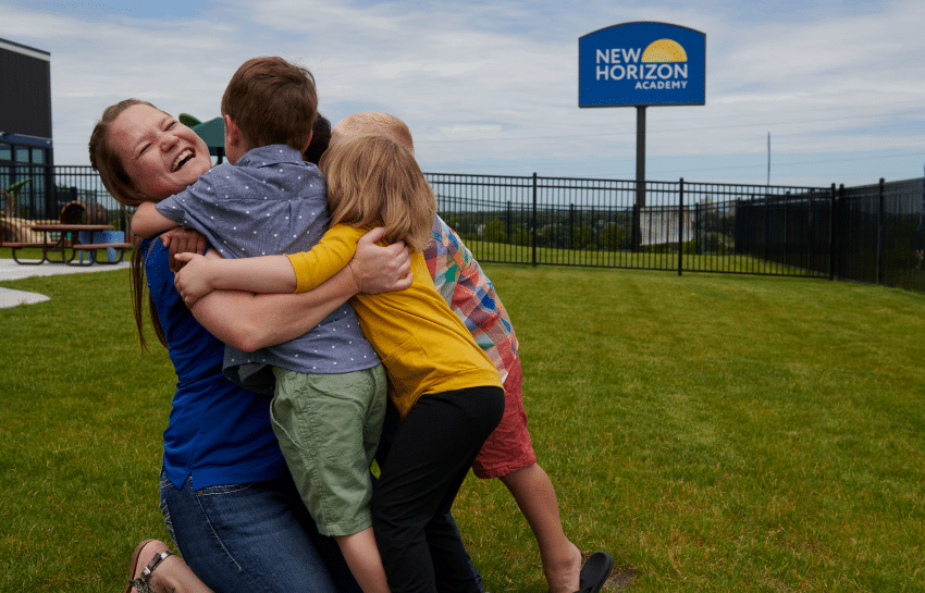 substitute teacher hugging daycare children at New Horizon Academy during work