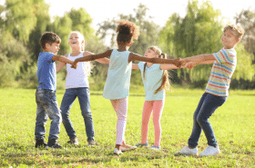 Group of children dancing in a circle together outside while playing dance games