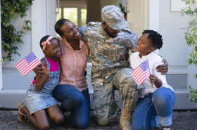 Daughter, mother, father dressed in military wear, and son celebrating Memorial Day while waving American flags