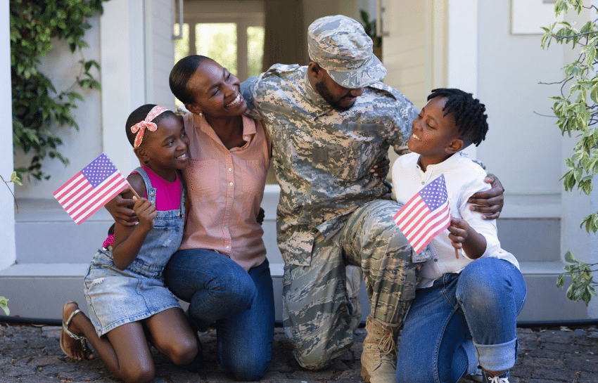 Daughter, mother, father dressed in military wear, and son celebrating Memorial Day while waving American flags