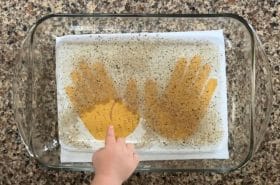 Child trying the handwashing experiment by sticking their finger in dish soap and then in a pepper filled bowl to watch the pepper germs scatter away