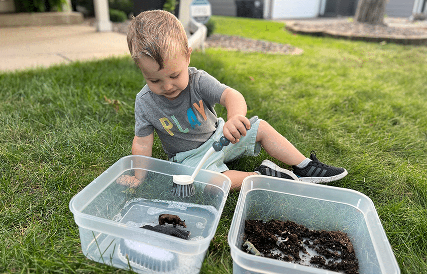 Toddler child washing toy farm animals for a sensory bin activity