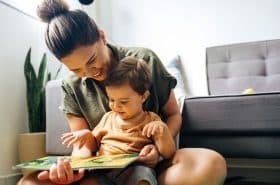 mother reading a storybook to her toddler on her lap