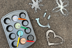 Paint, muffin tin, paintbrushes, and chalk materials to make diy sidewalk chalk paint outside