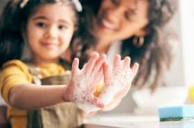 preschool child washing their hands with soap and water to stay healthy