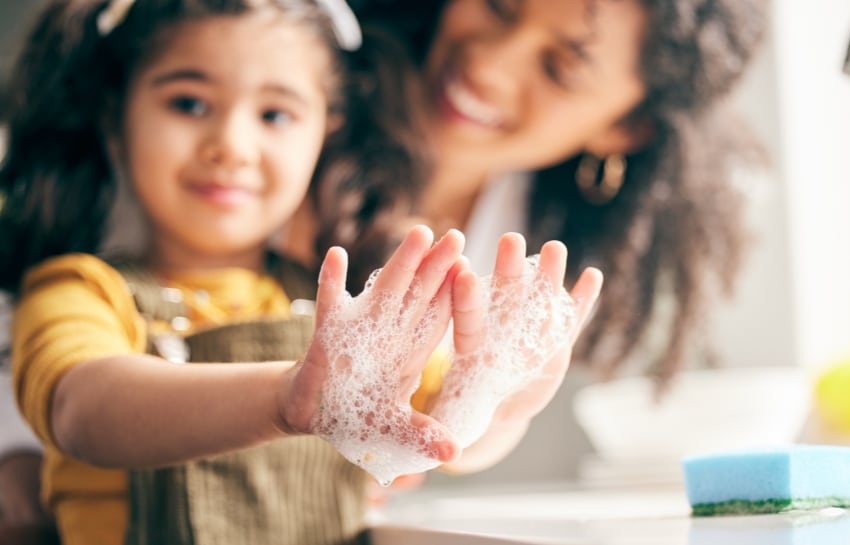 preschool child washing their hands with soap and water to stay healthy