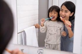 Parent and child brushing teeth together while practicing pediatric oral health tips