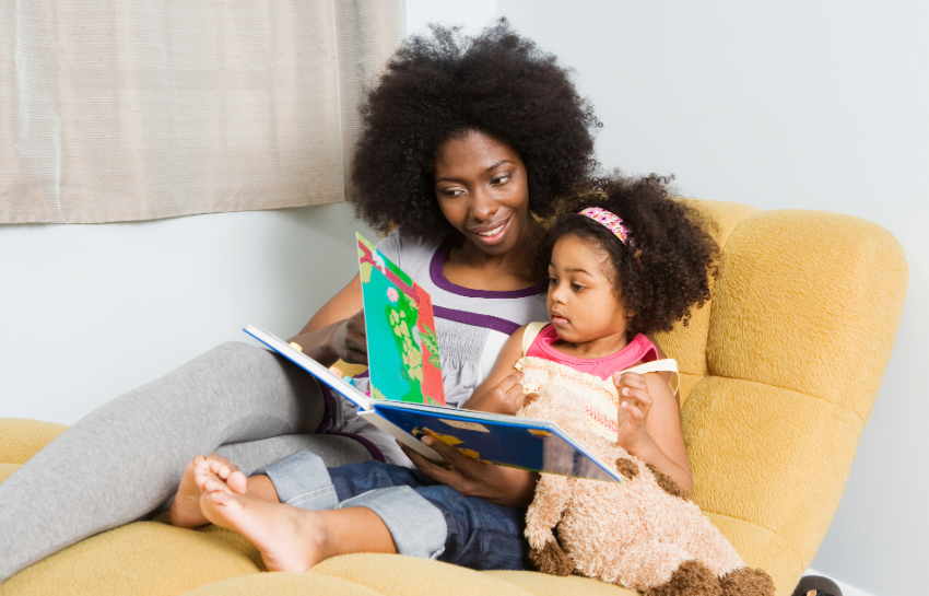 Mother reading a picture book to her preschool child, helping her develop strong reading habits