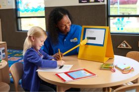 Teacher helping child with their writing skills in New Horizon Academy's preschool program