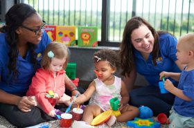 Daycare teachers playing with infants in New Horizon Academy daycare classroom