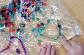 Child sorting bead colors through heart sensory bag