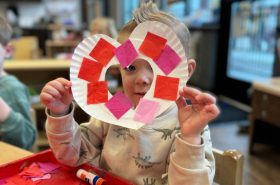 Preschool boy holding homemade Valentine's Day heart wreath craft