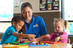 Preschool teacher doing a sensory activity with two preschool children in the classroom