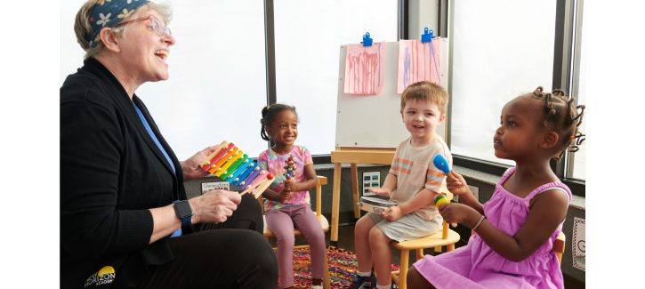 http://Childcare%20teacher%20playing%20musical%20instruments%20with%20group%20of%20pre-kindergarten%20children%20during%20class%20group%20time