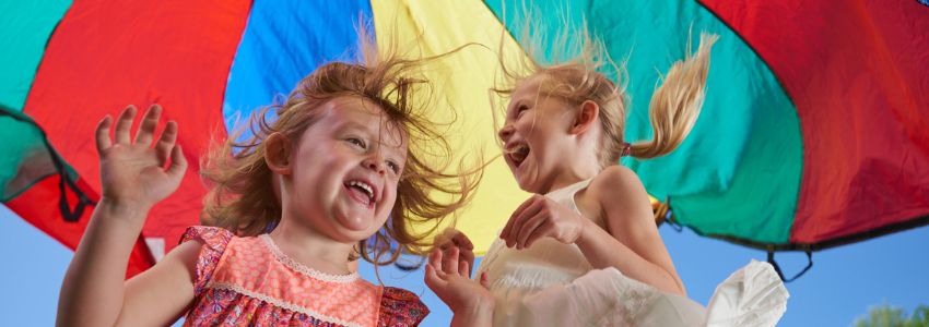 Children playing outside with parachute as part as New Horizon Academy's Camp Discovery summer program
