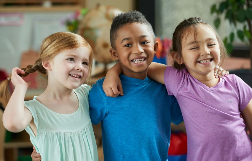 Diverse group of children hugging in their childcare classroom